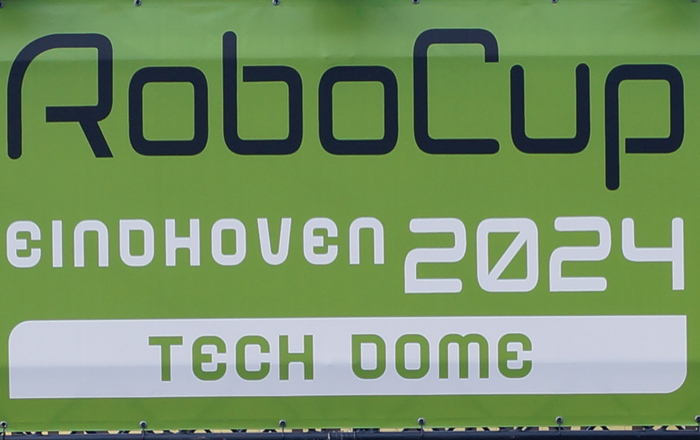 Vier Männer stehen vor dem Eingangsportal zum RoboCup 2024 